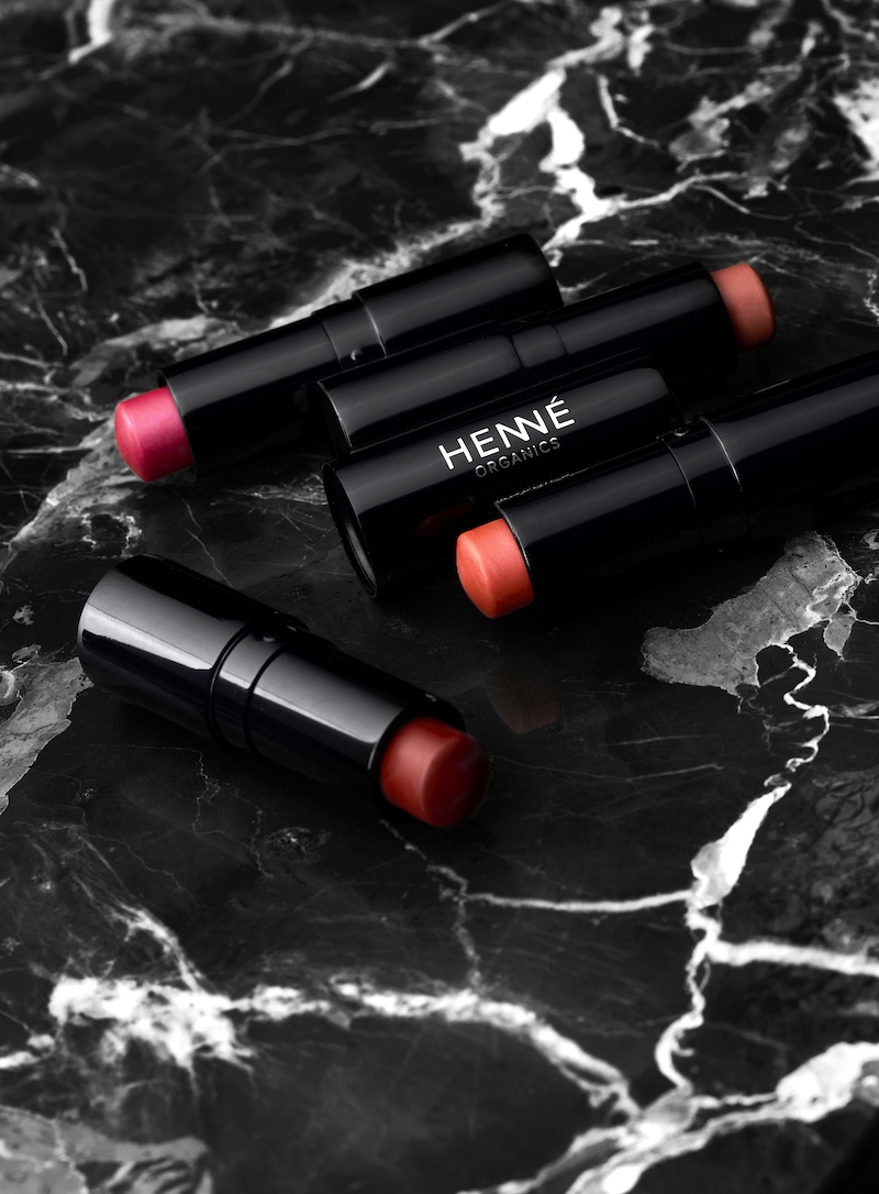 Four lip tints on black marble surface.