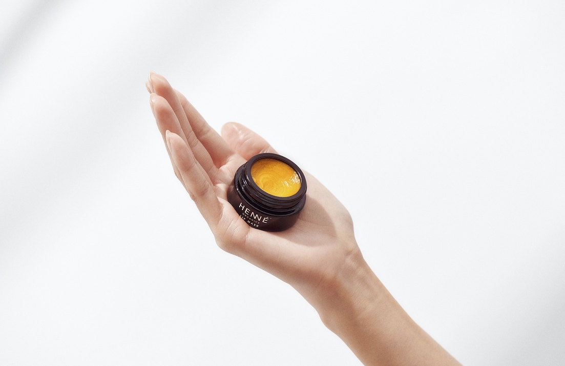 Woman holding Lip Mask with hand pointed upward.