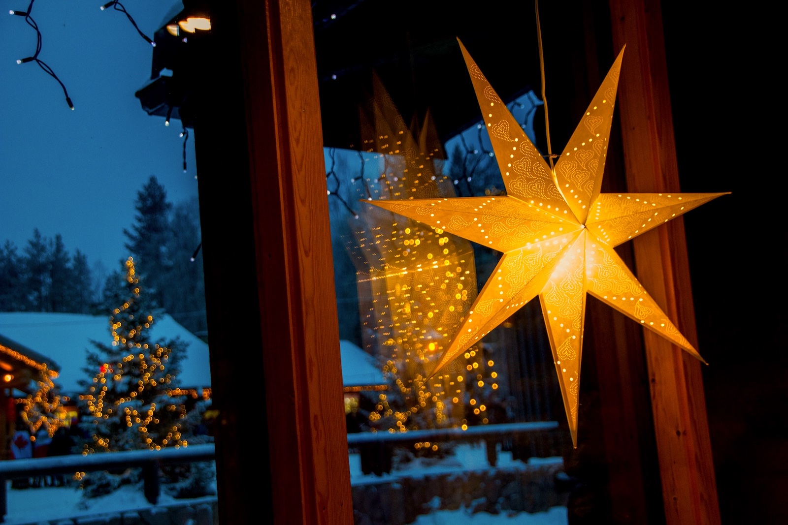 Christmas star hanging by window of a house in evening.